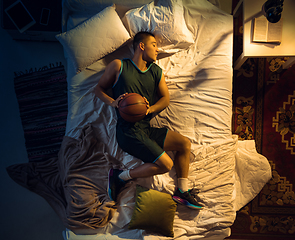 Image showing Top view of young professional basketball player sleeping at his bedroom in sportwear with ball