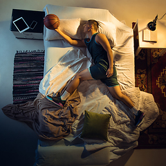 Image showing Top view of young professional basketball player sleeping at his bedroom in sportwear with ball