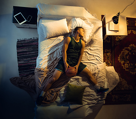 Image showing Top view of young professional basketball player sleeping at his bedroom in sportwear with ball