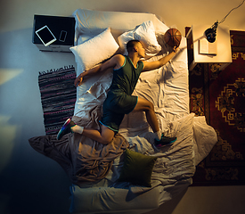 Image showing Top view of young professional basketball player sleeping at his bedroom in sportwear with ball