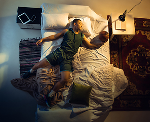 Image showing Top view of young professional basketball player sleeping at his bedroom in sportwear with ball