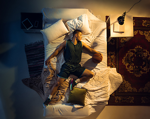 Image showing Top view of young professional basketball player sleeping at his bedroom in sportwear with ball