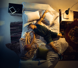 Image showing Top view of young professional basketball player sleeping at his bedroom in sportwear with ball