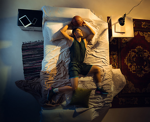 Image showing Top view of young professional basketball player sleeping at his bedroom in sportwear with ball