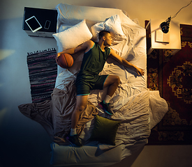 Image showing Top view of young professional basketball player sleeping at his bedroom in sportwear with ball