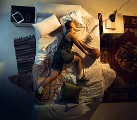 Image showing Top view of young professional basketball player sleeping at his bedroom in sportwear with ball