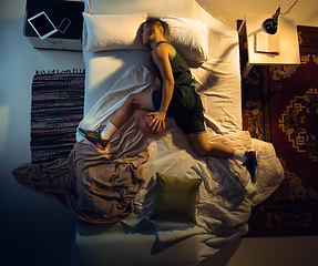 Image showing Top view of young professional basketball player sleeping at his bedroom in sportwear with ball