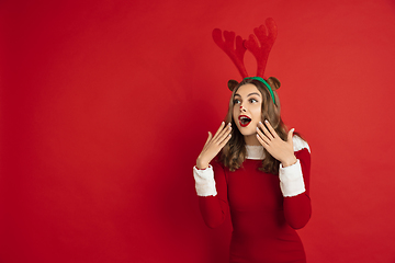 Image showing Beautiful woman like Christmas deer isolated on red background. Concept of 2021 New Year\'s, winter mood, holidays.