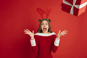 Image showing Beautiful woman like Christmas deer isolated on red background. Concept of 2021 New Year\'s, winter mood, holidays.