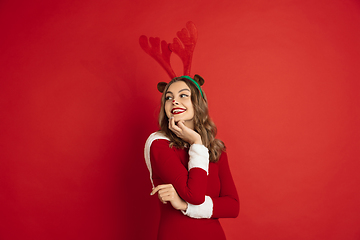 Image showing Beautiful woman like Christmas deer isolated on red background. Concept of 2021 New Year\'s, winter mood, holidays.