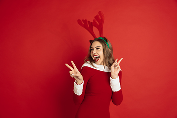 Image showing Beautiful woman like Christmas deer isolated on red background. Concept of 2021 New Year\'s, winter mood, holidays.