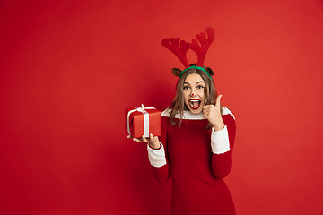 Image showing Beautiful woman like Christmas deer isolated on red background. Concept of 2021 New Year\'s, winter mood, holidays.