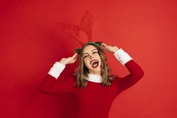 Image showing Beautiful woman like Christmas deer isolated on red background. Concept of 2021 New Year\'s, winter mood, holidays.