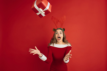 Image showing Beautiful woman like Christmas deer isolated on red background. Concept of 2021 New Year\'s, winter mood, holidays.