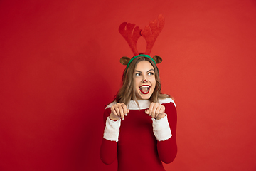 Image showing Beautiful woman like Christmas deer isolated on red background. Concept of 2021 New Year\'s, winter mood, holidays.