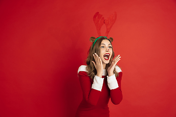 Image showing Beautiful woman like Christmas deer isolated on red background. Concept of 2021 New Year\'s, winter mood, holidays.