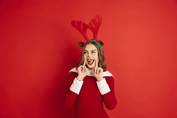 Image showing Beautiful woman like Christmas deer isolated on red background. Concept of 2021 New Year\'s, winter mood, holidays.