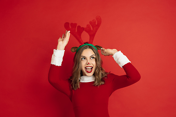 Image showing Beautiful woman like Christmas deer isolated on red background. Concept of 2021 New Year\'s, winter mood, holidays.