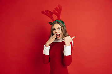 Image showing Beautiful woman like Christmas deer isolated on red background. Concept of 2021 New Year\'s, winter mood, holidays.