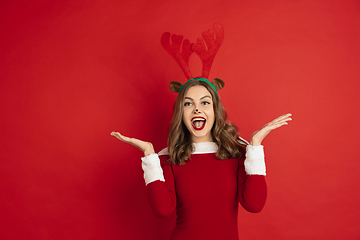 Image showing Beautiful woman like Christmas deer isolated on red background. Concept of 2021 New Year\'s, winter mood, holidays.