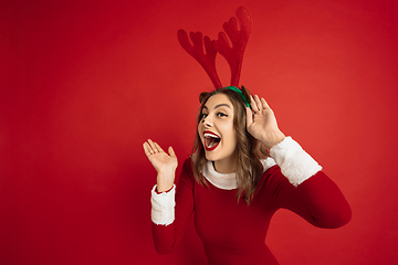 Image showing Beautiful woman like Christmas deer isolated on red background. Concept of 2021 New Year\'s, winter mood, holidays.