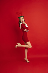 Image showing Beautiful woman like Christmas deer isolated on red background. Concept of 2021 New Year\'s, winter mood, holidays.