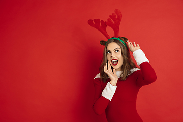 Image showing Beautiful woman like Christmas deer isolated on red background. Concept of 2021 New Year\'s, winter mood, holidays.