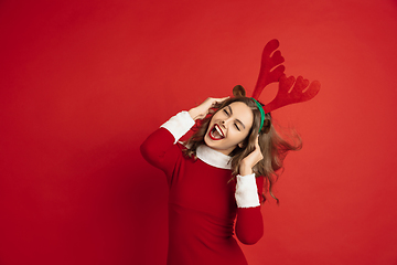 Image showing Beautiful woman like Christmas deer isolated on red background. Concept of 2021 New Year\'s, winter mood, holidays.