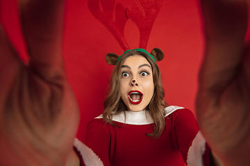 Image showing Beautiful woman like Christmas deer isolated on red background. Concept of 2021 New Year\'s, winter mood, holidays.