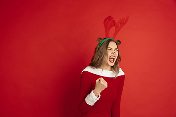 Image showing Beautiful woman like Christmas deer isolated on red background. Concept of 2021 New Year\'s, winter mood, holidays.