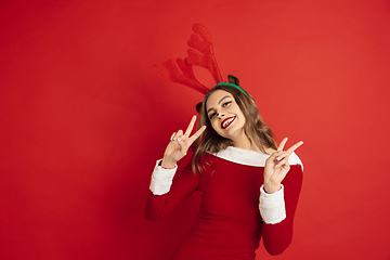 Image showing Beautiful woman like Christmas deer isolated on red background. Concept of 2021 New Year\'s, winter mood, holidays.