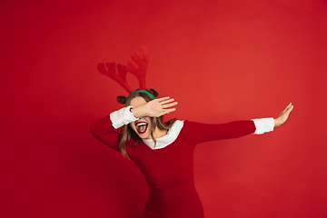 Image showing Beautiful woman like Christmas deer isolated on red background. Concept of 2021 New Year\'s, winter mood, holidays.