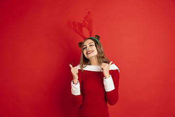 Image showing Beautiful woman like Christmas deer isolated on red background. Concept of 2021 New Year\'s, winter mood, holidays.