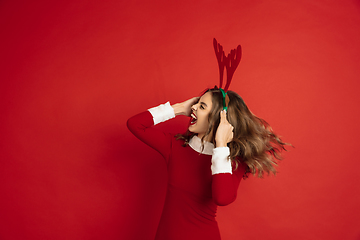 Image showing Beautiful woman like Christmas deer isolated on red background. Concept of 2021 New Year\'s, winter mood, holidays.