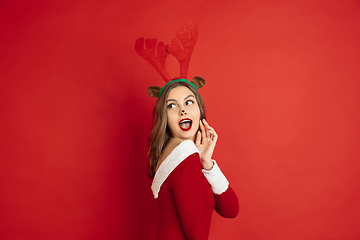 Image showing Beautiful woman like Christmas deer isolated on red background. Concept of 2021 New Year\'s, winter mood, holidays.