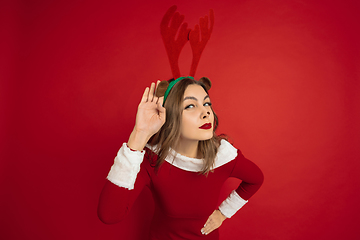 Image showing Beautiful woman like Christmas deer isolated on red background. Concept of 2021 New Year\'s, winter mood, holidays.