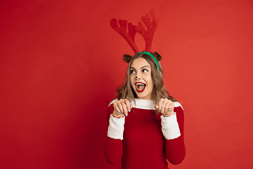 Image showing Beautiful woman like Christmas deer isolated on red background. Concept of 2021 New Year\'s, winter mood, holidays.