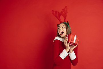 Image showing Beautiful woman like Christmas deer isolated on red background. Concept of 2021 New Year\'s, winter mood, holidays.