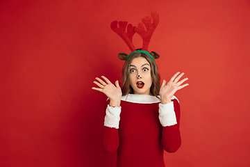 Image showing Beautiful woman like Christmas deer isolated on red background. Concept of 2021 New Year\'s, winter mood, holidays.