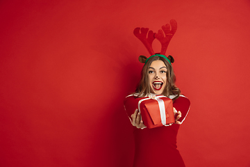 Image showing Beautiful woman like Christmas deer isolated on red background. Concept of 2021 New Year\'s, winter mood, holidays.