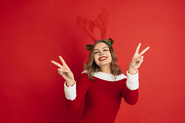 Image showing Beautiful woman like Christmas deer isolated on red background. Concept of 2021 New Year\'s, winter mood, holidays.