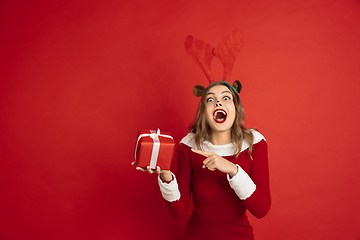 Image showing Beautiful woman like Christmas deer isolated on red background. Concept of 2021 New Year\'s, winter mood, holidays.