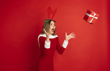 Image showing Beautiful woman like Christmas deer isolated on red background. Concept of 2021 New Year\'s, winter mood, holidays.