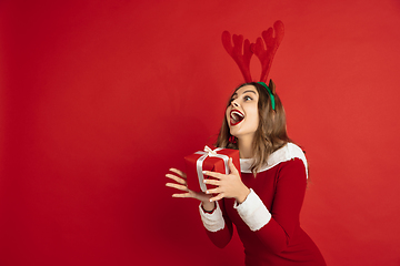 Image showing Beautiful woman like Christmas deer isolated on red background. Concept of 2021 New Year\'s, winter mood, holidays.