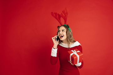 Image showing Beautiful woman like Christmas deer isolated on red background. Concept of 2021 New Year\'s, winter mood, holidays.