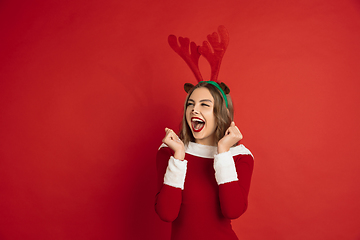 Image showing Beautiful woman like Christmas deer isolated on red background. Concept of 2021 New Year\'s, winter mood, holidays.