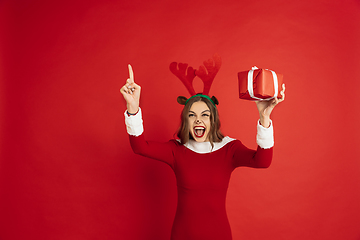 Image showing Beautiful woman like Christmas deer isolated on red background. Concept of 2021 New Year\'s, winter mood, holidays.