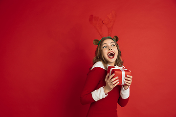 Image showing Beautiful woman like Christmas deer isolated on red background. Concept of 2021 New Year\'s, winter mood, holidays.