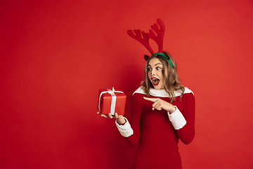 Image showing Beautiful woman like Christmas deer isolated on red background. Concept of 2021 New Year\'s, winter mood, holidays.