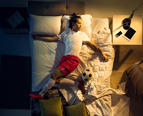 Image showing Top view of young professional football, soccer player sleeping at his bedroom in sportwear with ball